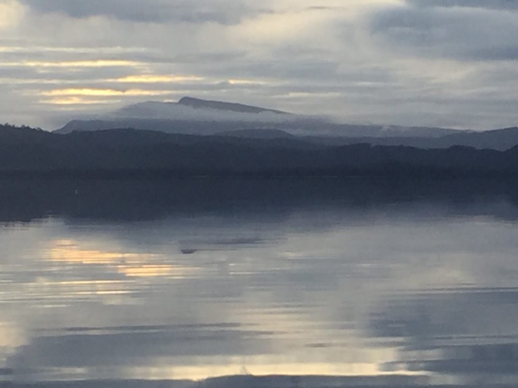 Misty terrain in the distance, calm waters nearby